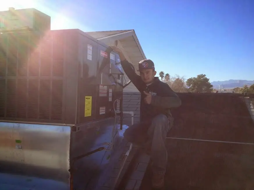 HVAC technician performing Air Duct Cleaning on a rooftop unit in Atchison